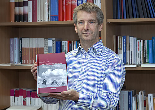 Professor Mario Niemann zeigt stolz sein Buch mit dem Titel „Beständiger Wandel“. (Foto: Universität Rostock/Julia Tetzke). 