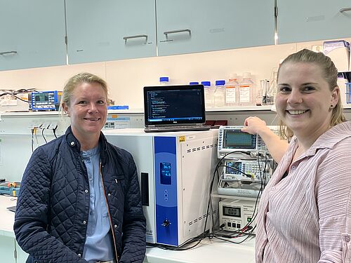 Dr. Nadja Engel und Laura Lembcke im Zelllabor. Im Hintergrund die funktionelle, elektrische Einheit sowie das Kontrollsystem für die elektrische Stimulation der Implantate (Foto: Joachim Mangler).
