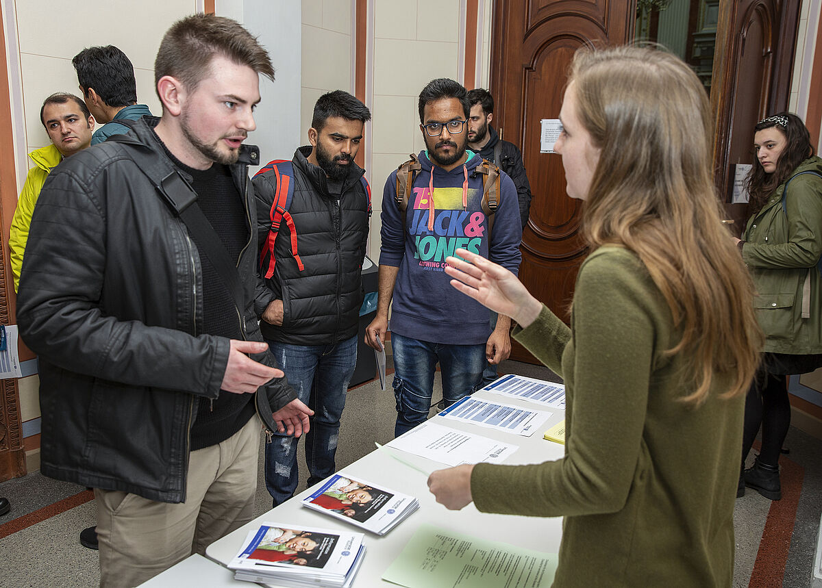 Bild 12: Mitarbeiterin erklärt einem ausländischen Studenten etwas