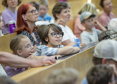 Kinder-Uni Rostock 2026 (Foto: Robert Leppin, Universität Rostock). Kinder und Erwachsene sitzen in einem Hörsaal.