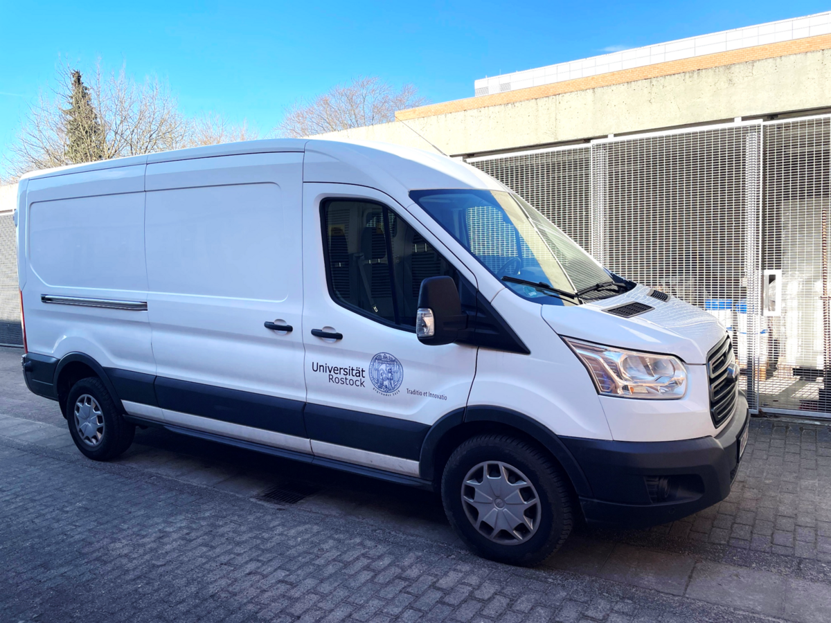 Das Foto zeigt einen weißen Transporter mit dem Logo der Universität Rostock auf der Tür. Der Transporter wird regelmäßig für die Entsorgungsfahrten verwendet.