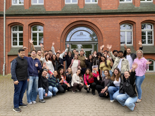 Teilnehmende der EU-CONEXUS Spring School „AI, Data Visualisation & Smart Industry Technologies“ posieren für ein Gruppenfoto vor der Universität Rostock.