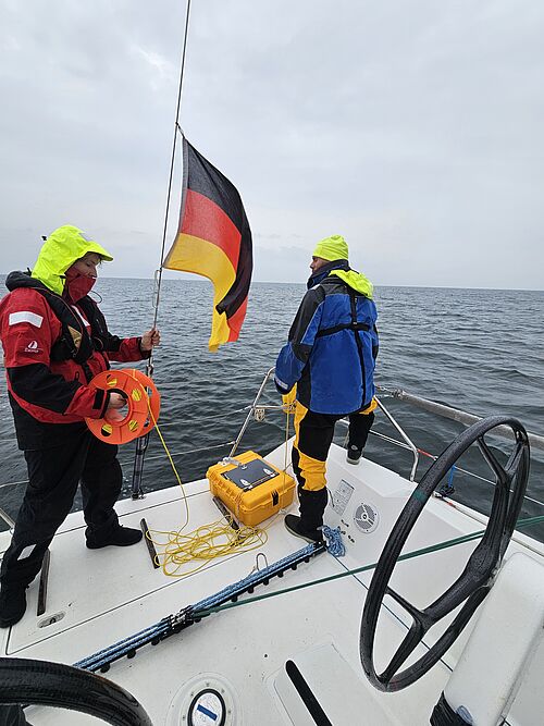 Zwei Studierende an Bord der UNIVERSITAS beim Segeln, ausgestattet mit Messinstrumenten für das Forschungsprojekt Sail CONEXUS.