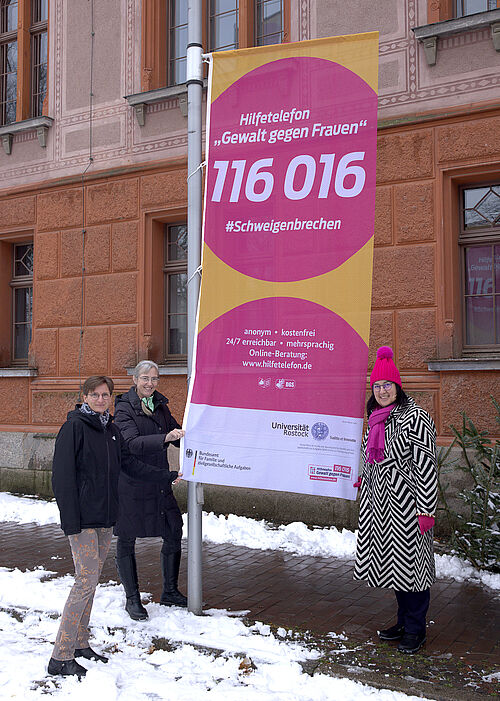 Dr. H. Jander, Prof. Dr. N. Wrage-Mönnig und Rektorin Prof. Dr. E. Prommer (v.l.) neben der gehissten Fahne mit der Nummer des Hilfetelefons. (Julia Tetzke/Universität Rostock) Dr. H. Jander, Prof. Dr. N. Wrage-Mönnig und Rektorin Prof. Dr. E. Prommer (v.l.) neben der gehissten Fahne mit der Nummer des Hilfetelefons. (Julia Tetzke/Universität Rostock)