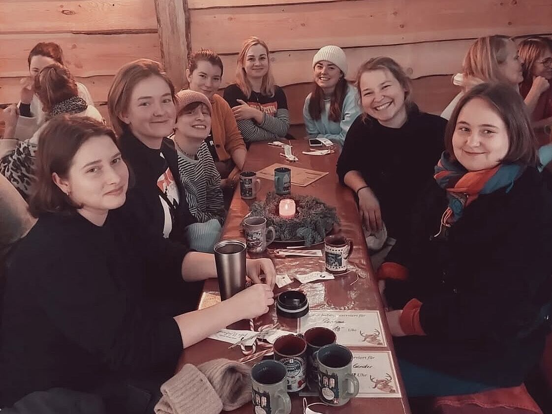 Junge Frauen sitzen gemeinsam an einem Tisch und feiern.