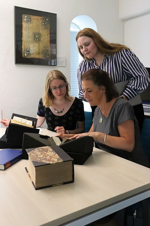 Ein Teil der relevanten Literatur ist in der Sondersammlung der Universitätsbuchhandlung vorhanden, wo Franziska Schreiber, Professorin Stephanie Wodianka (v.l) und Julia Borzinski (stehend) recherchieren (Foto: Anna Fröhlich).