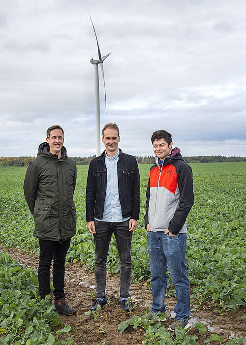 Die drei Doktoranden Johannes Luthe, Andreas Schulze und Stephan Häusler (v. l.) vor der im Projekt DynAWind² untersuchten Windenergieanlage des Rostocker Unternehmens W2E. (Foto: Universität Rostock/Julia Tetzke).
