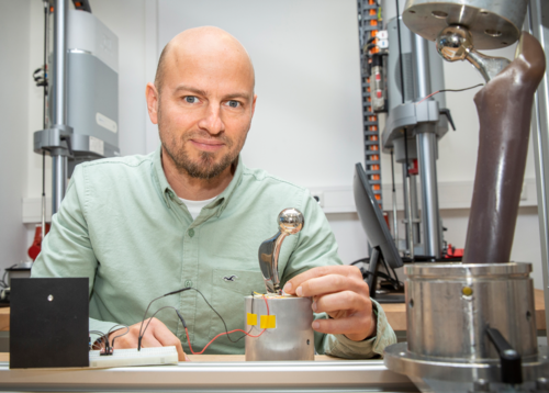 Die Hüftendoprothese wird mit einer Piezo-Keramik ausgestattet, um mechanische Energie in elektrische Energie umzuwandeln. Dr. Daniel Klüß zeigt hier den Funktionsdemonstrator der intelligenten Hüftendoprothese (Foto: Universität Rostock/Thomas Rahr). 