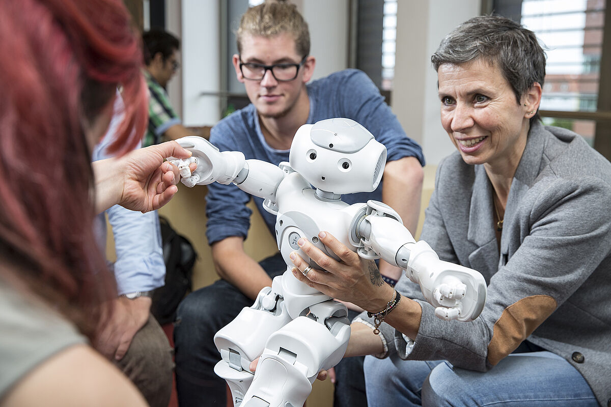 Bild 11: Dozent und Studenten beschäftigen sich mit einem kleinen Roboter