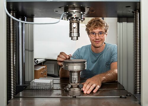 Der 27 Jahre junge Wissenschaftler Jan-Oliver Saß an der Prüfmaschine zur Charakterisierung der mechanischen Eigenschaften der neuartigen Titanlegierungen (Foto: Universität Rostock/Thomas Rahr).