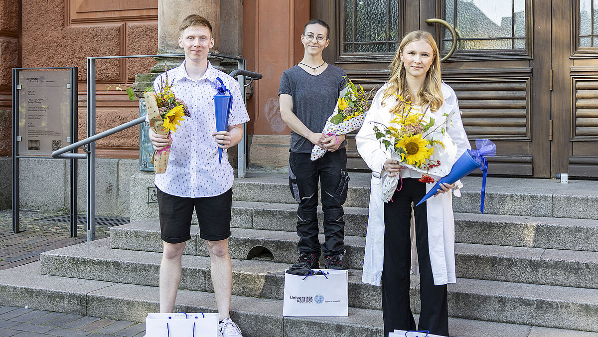 neue Auszubildende vor dem Eingang des Universitätshauptgebäudes