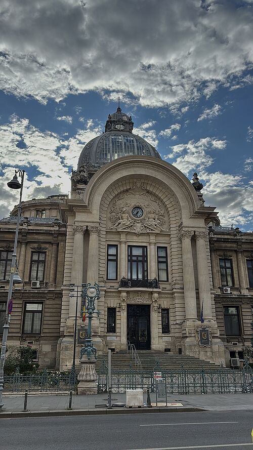 Historisches Gebäude mit großer Glaskuppel und Uhr am Portal – der CEC-Palast in Bukarest.