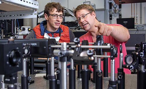 Bildunterschrift: Professor Alexander Szameit (rechts im Bild) bespricht mit Lukas Maczewsky im Laserlabor der Universität Rostock den experimentellen Aufbau